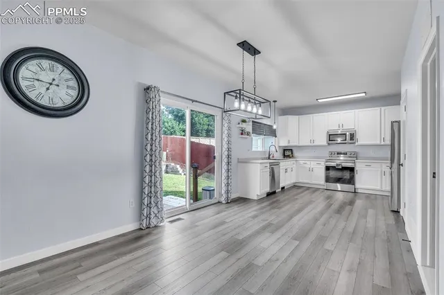 a view of a kitchen with fridge and wooden floor