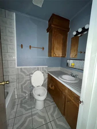 a bathroom with a granite countertop sink toilet and mirror