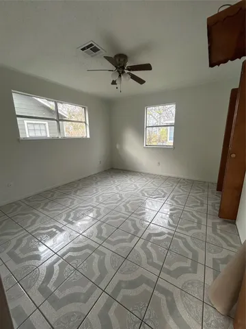 an empty room with windows and fan