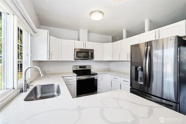 a kitchen with stainless steel appliances granite countertop a refrigerator sink and white cabinets