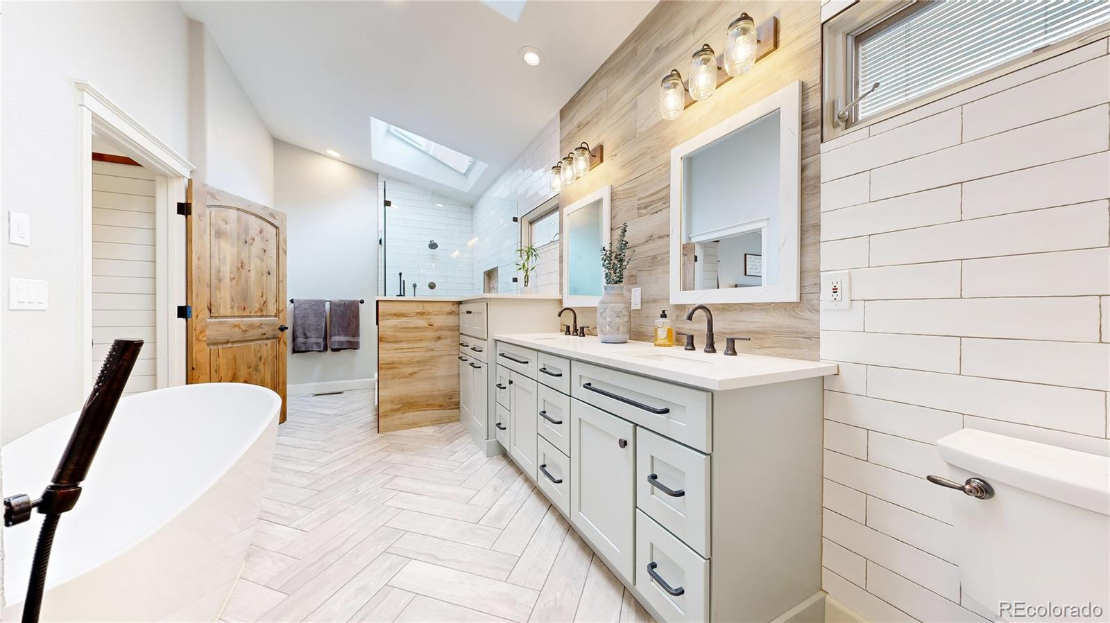 5575 Spring Glade Road Loveland, CO 80538 - Photo 19 of 49 a bathroom with a double vanity sink a mirror and a bathtub