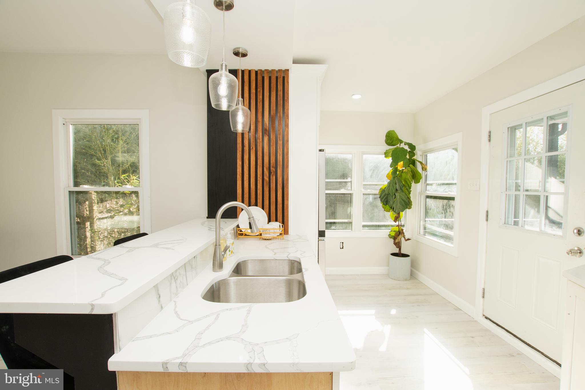 a kitchen with a sink a counter top space and living room view
