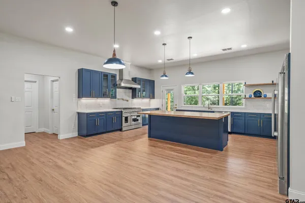a large kitchen with stainless steel appliances kitchen island a large counter top a sink cabinets and wooden floor