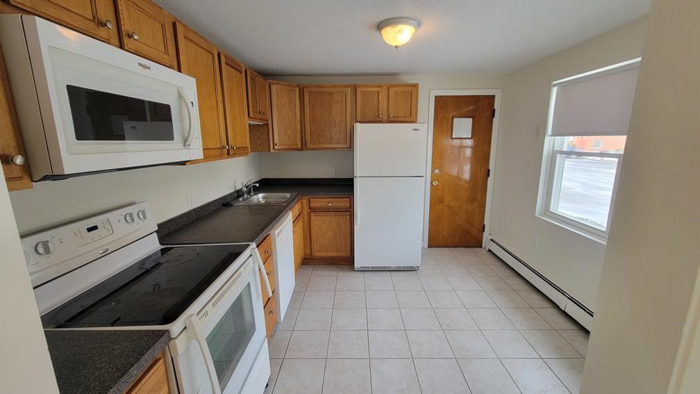6 Whitman Road, Unit 6 Waltham, MA 02453 - Photo 4 of 12 a kitchen with a refrigerator and a stove top oven