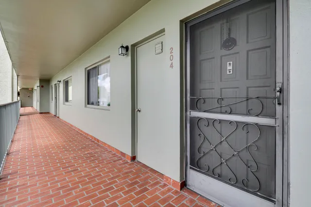 a view of a hallway with wooden floor and a bathroom