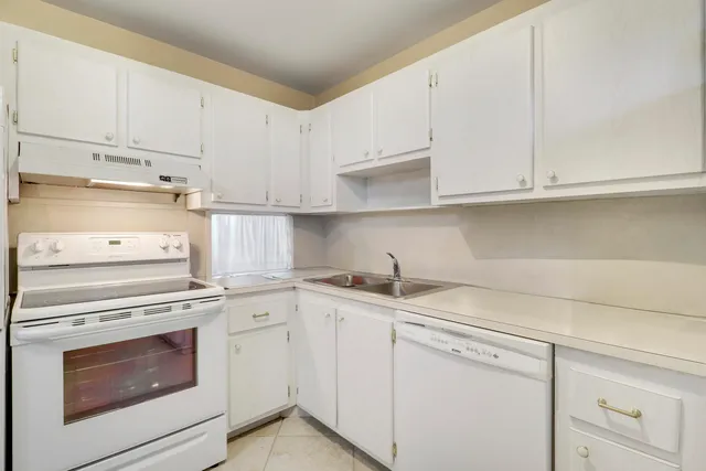 a kitchen with granite countertop white cabinets and white appliances