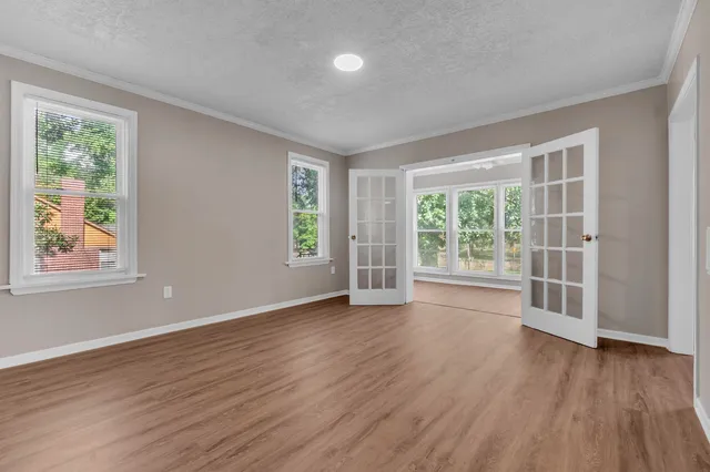 a view of an empty room with wooden floor and a window