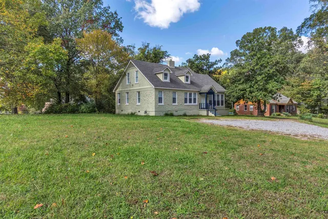 a view of a house with a big yard and large trees