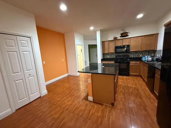 a kitchen with stainless steel appliances granite countertop a stove top oven a sink and a refrigerator