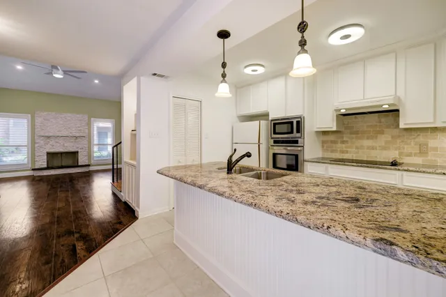 a kitchen with kitchen island a sink stainless steel appliances and a counter top space