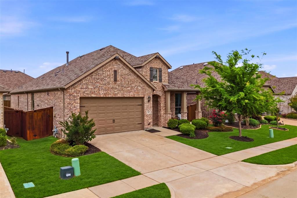 1429 Eclipse Road Aubrey, TX 76227 - Photo 2 of 37 The property features a brick exterior, an attached garage, a well-maintained lawn, and mature landscaping