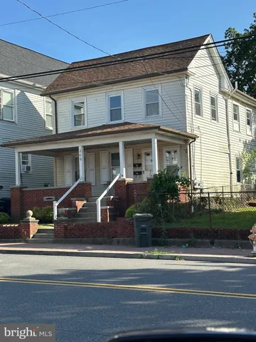 a view of a white house with a couches and potted plants