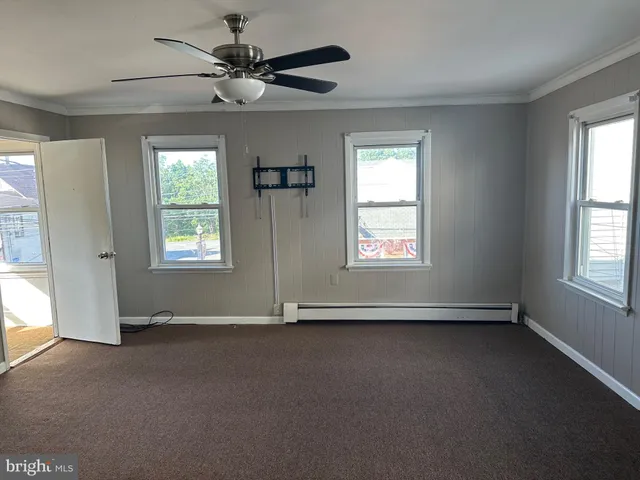 an empty room with windows and fan