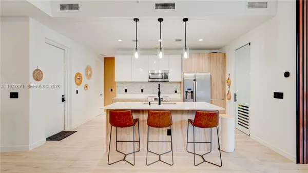 a view of kitchen with stainless steel appliances kitchen island granite countertop a refrigerator and a sink