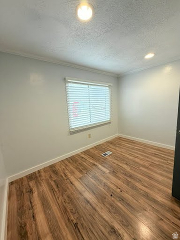 2491 Highway 89, Unit 114 Pleasant View, UT 84404 - Photo 17 of 18 Unfurnished room with dark wood-style floors, a textured ceiling, and ornamental molding