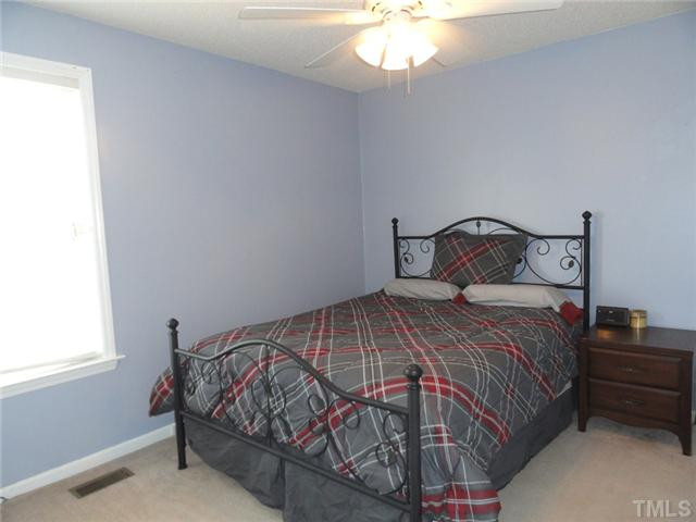 297 Rosa Circle Willow Spring, NC 27592 - Photo 18 of 23 a bedroom with a bed and a chandelier