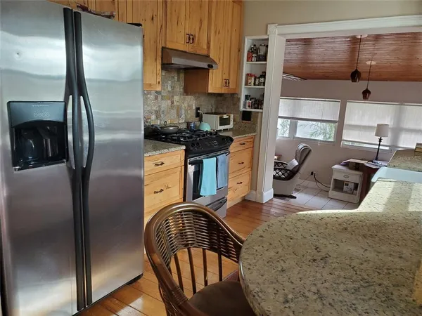 a kitchen with stainless steel appliances granite countertop a refrigerator a stove and a sink with large window