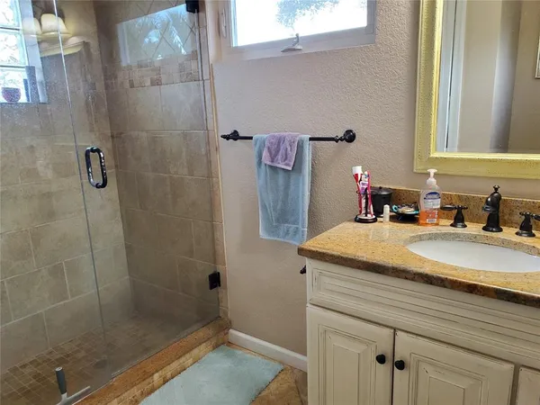 a bathroom with a granite countertop sink a shower and a mirror