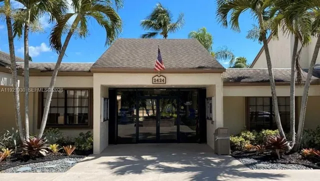 a view of a white house next to a yard with potted plants