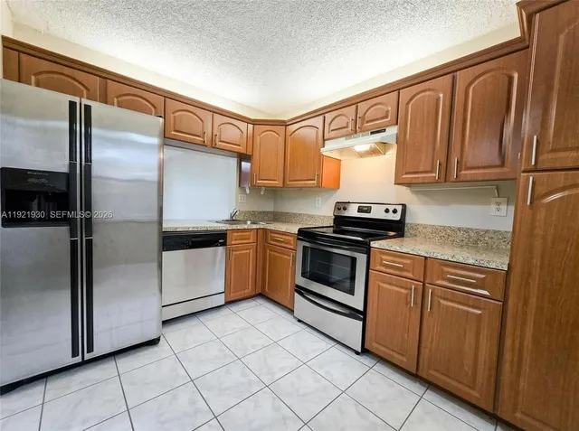 a kitchen with granite countertop a sink stainless steel appliances and cabinets