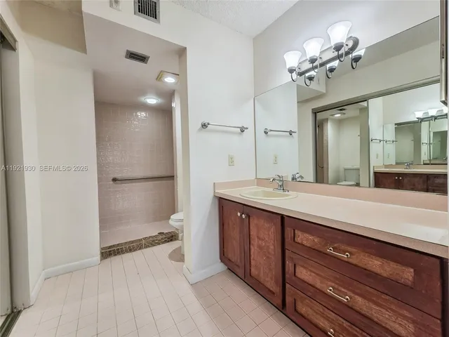 a spacious bathroom with a granite countertop sink a toilet and a mirror