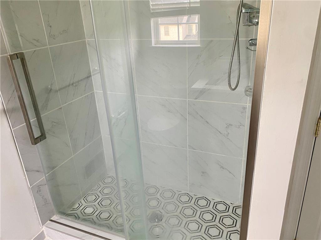 5494 Spring Ridge Drive West Macungie, PA 18062 - Photo 11 of 14 A glass-enclosed shower showcases marble-patterned wall tiles and patterned hexagon floor tile.