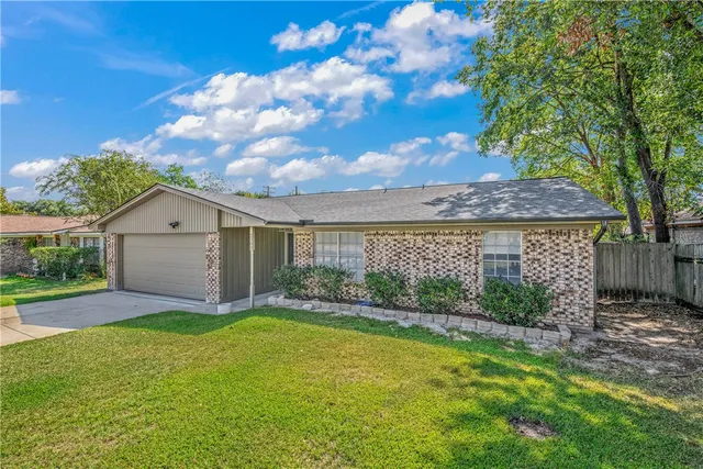a view of a house with a yard and large tree