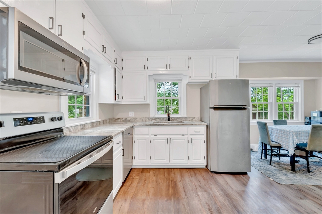 295 Harkness Avenue Springfield, MA 01118 - Photo 7 of 39 a kitchen with a refrigerator a stove a sink dishwasher and white cabinets with wooden floor