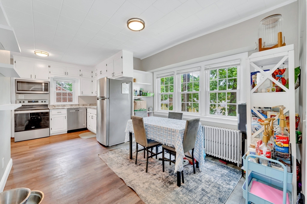 295 Harkness Avenue Springfield, MA 01118 - Photo 10 of 39 a kitchen with stainless steel appliances a stove a refrigerator and a dining table with wooden floor