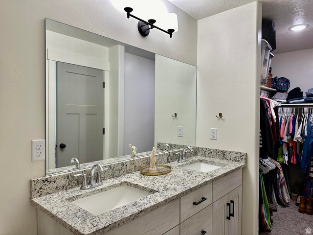 4349 Half Mile Road East Enoch, UT 84721 - Photo 14 of 36 Full bath featuring double vanity, a spacious closet, and a textured ceiling