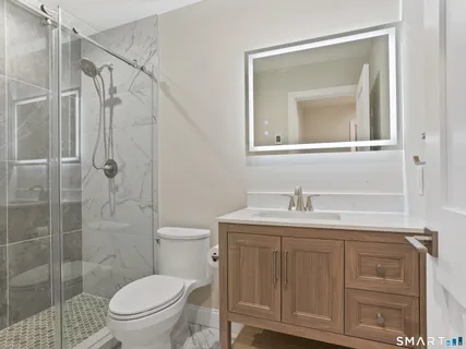a bathroom with a granite countertop sink toilet a mirror and shower