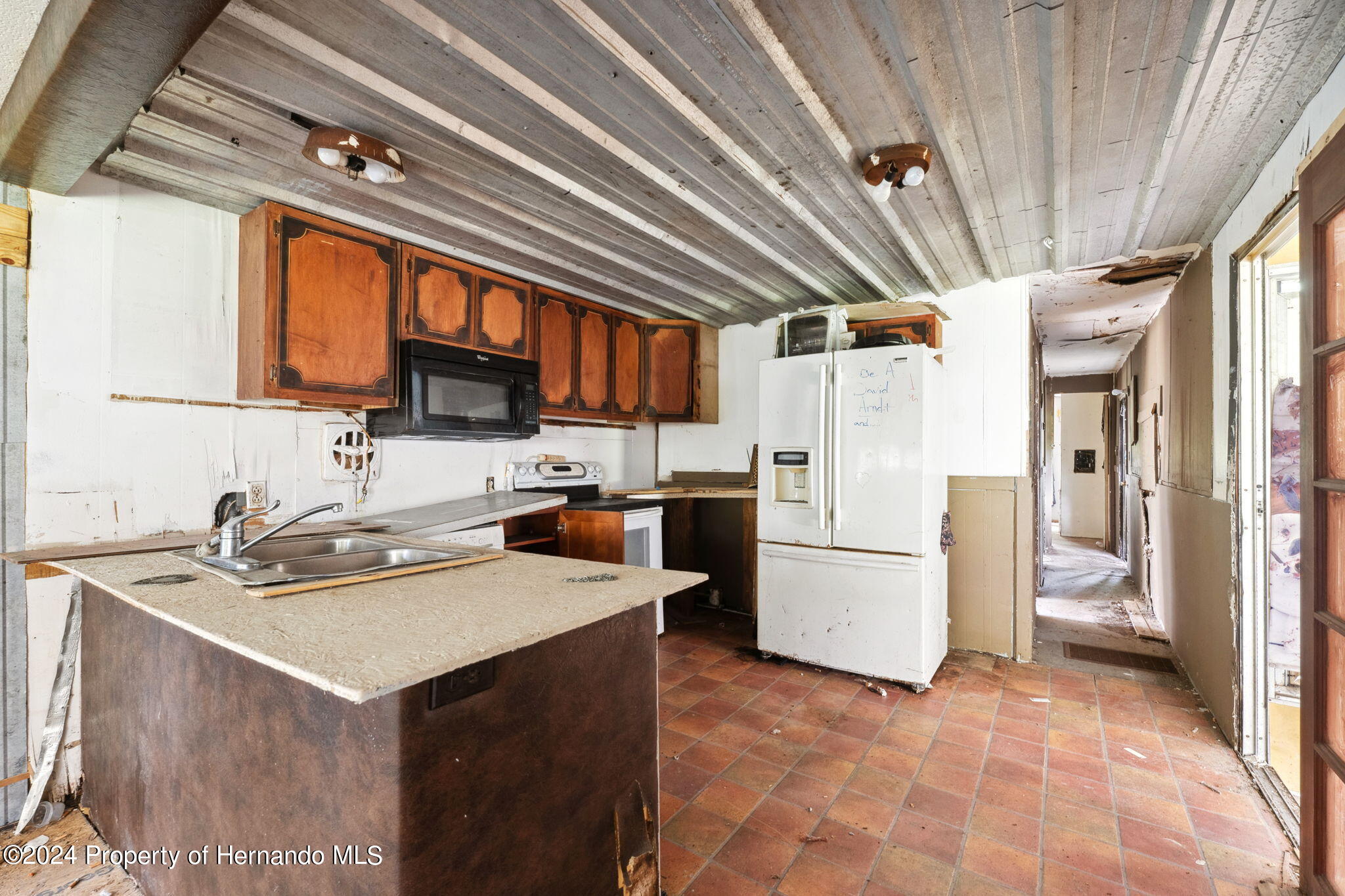 11017 Knuckey Road Weeki Wachee, FL 34614 - Photo 9 of 39 a kitchen with a sink a refrigerator and cabinets