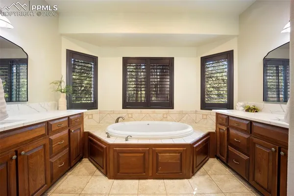 a spacious bathroom with a tub a sink and large window