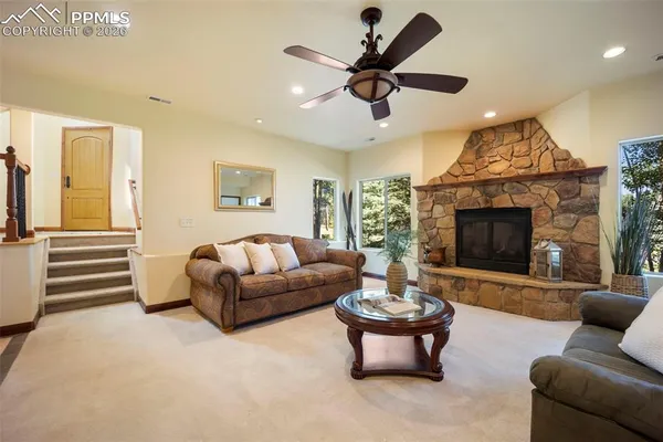 a living room with furniture a fireplace and a ceiling fan