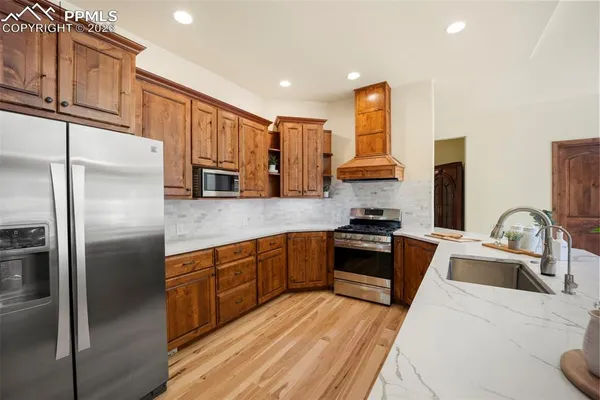 a kitchen with stainless steel appliances granite countertop a refrigerator sink and stove