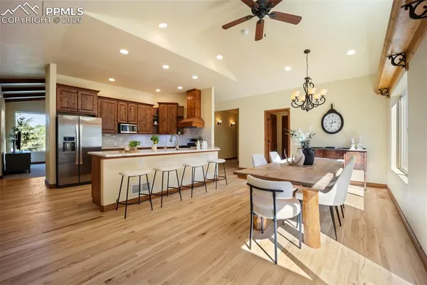 a kitchen with stainless steel appliances kitchen island granite countertop a table chairs and a refrigerator
