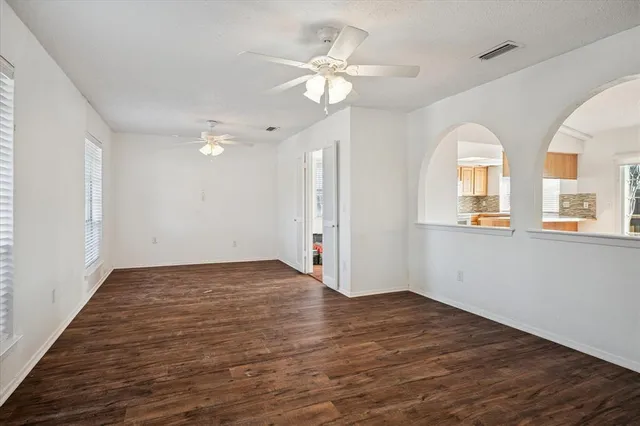 a view of an empty room with wooden floor and a window