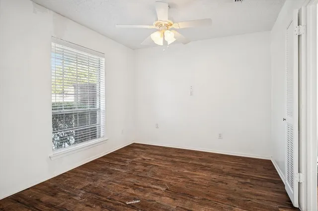 a view of empty room with wooden floor and fan