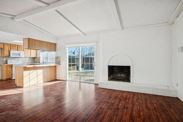 a view of a kitchen with wooden floor and a fireplace