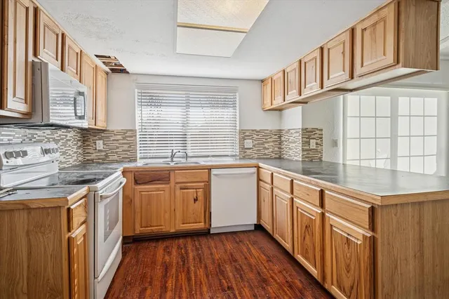 a kitchen with stainless steel appliances granite countertop a sink and wooden cabinets