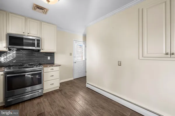 a kitchen with granite countertop white cabinets stainless steel appliances and wooden floor