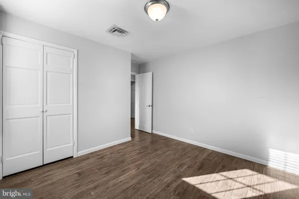 an empty room with wooden floor and natural light