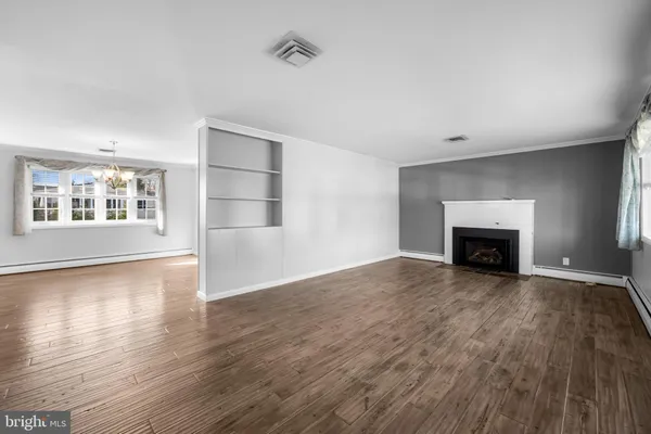 an empty room with wooden floor fireplace and windows