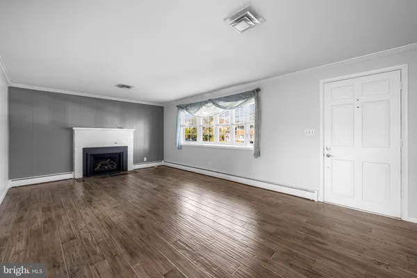 an empty room with wooden floor fireplace and windows