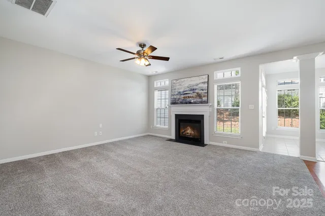 an empty room with windows fireplace and fan