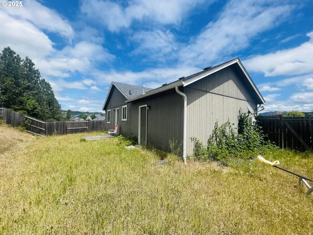 a backyard of a house with plants and large tree