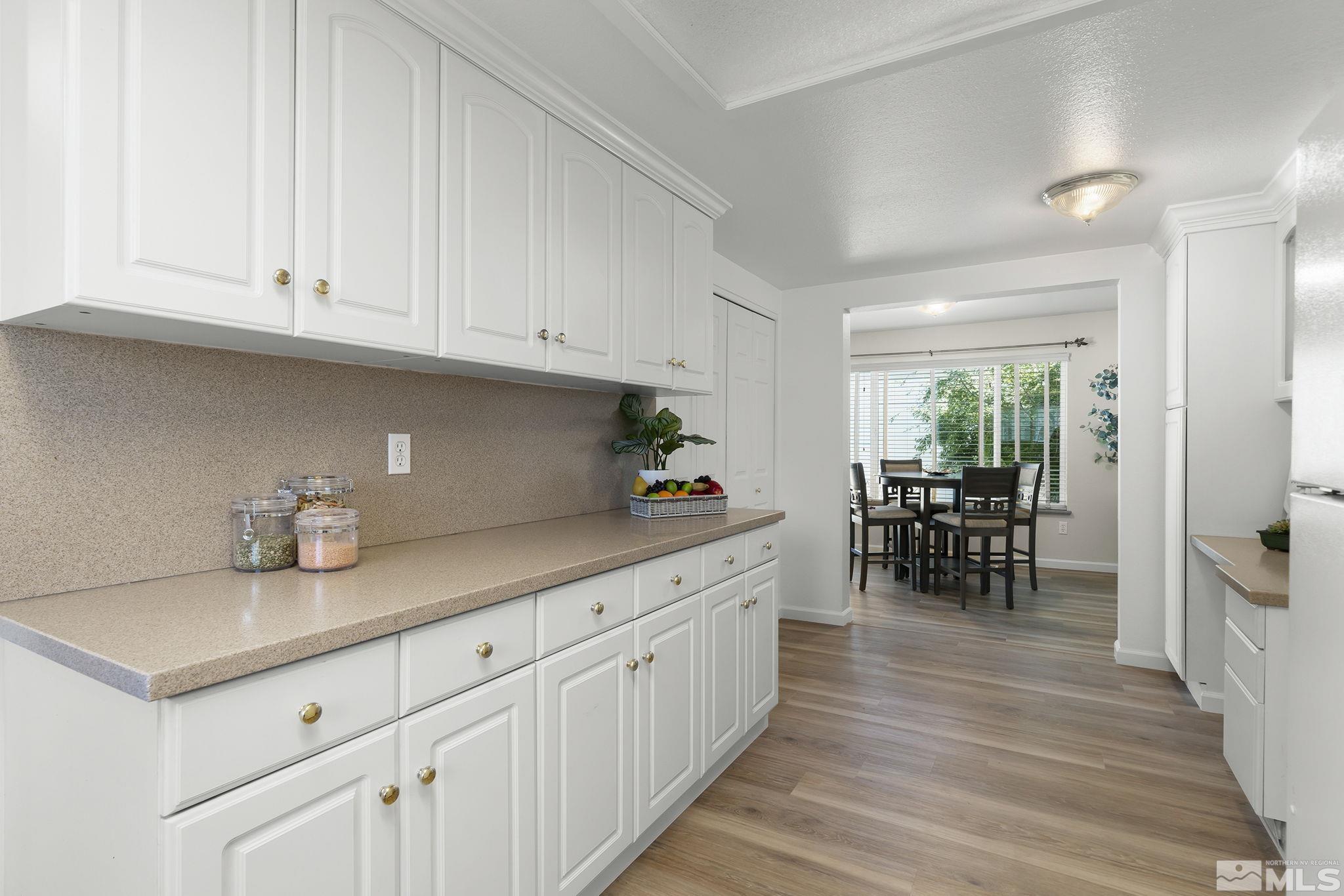 1220 Laredo Court Reno, NV 89503 - Photo 7 of 29 a kitchen with white cabinets and wooden floors