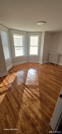 a view of empty room with window and wooden floor