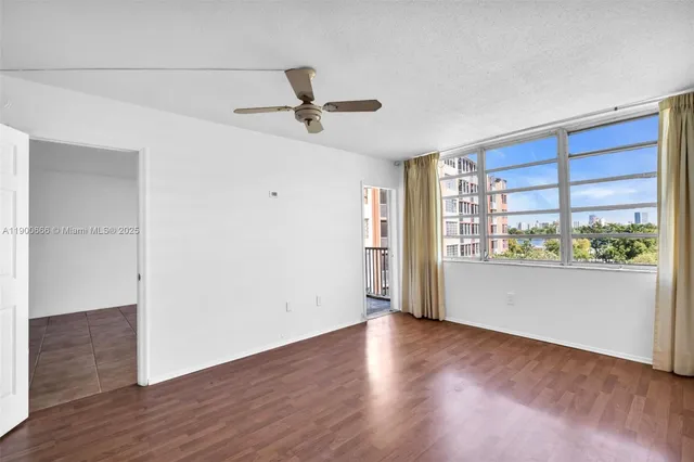 a view of empty room with wooden floor and fan
