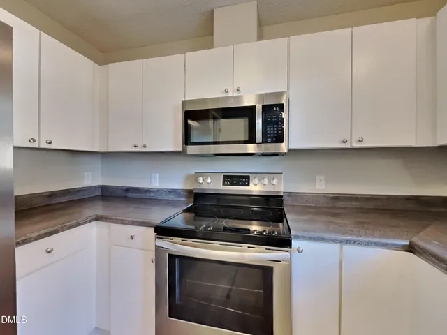 a kitchen with granite countertop white cabinets and stainless steel appliances
